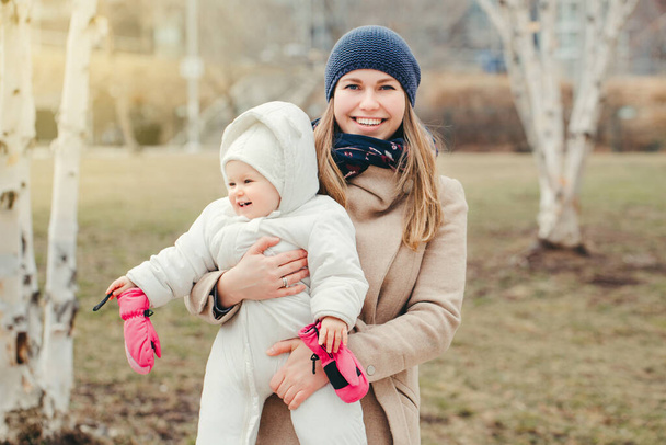Χαρούμενη χαμογελαστή λευκή μητέρα που κρατάει την κόρη της έξω. Γιορτές της Μητέρας. Αυθεντική οικογένεια τρόπου ζωής με βρέφος παιδί παιδί.  - Φωτογραφία, εικόνα