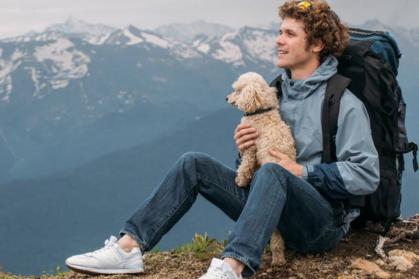 positive hiker with pet resting on the peak of the mountain after long travel - Foto, Imagem