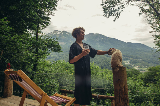 handsome guy in black gown is petting a dog - Foto, afbeelding