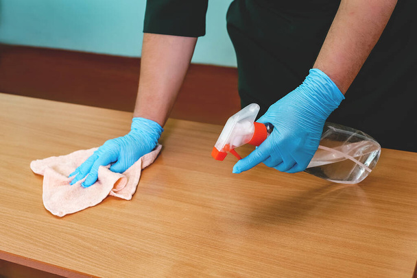 Une enseignante nettoie les tables avec du désinfectant avant l'arrivée des enfants en classe - Photo, image