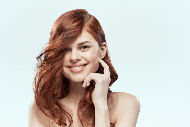 Гарненька жінка тримає волосся посмішка косметичний спосіб життя голі плечі зачіска догляд за чарівним світлим фоном
 - Фото, зображення