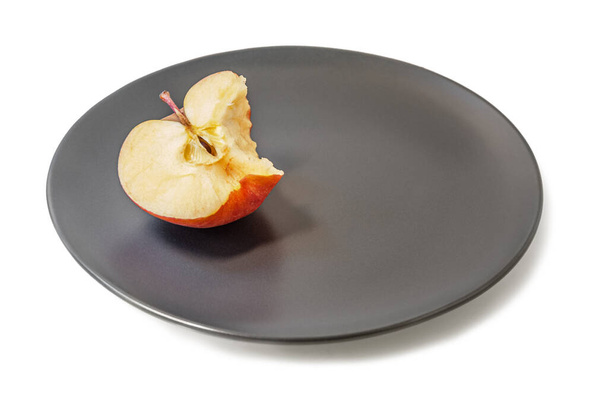 bitten red apple on a black ceramic plate isolated on white - Photo, Image