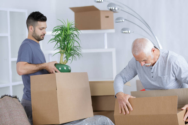 portrait of men unpacking boxes - Foto, imagen