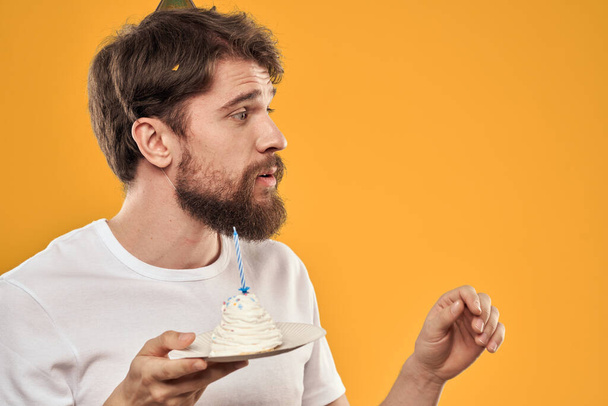 Handsome man with a beard and in a cap celebrating a birthday party yellow background - Foto, immagini