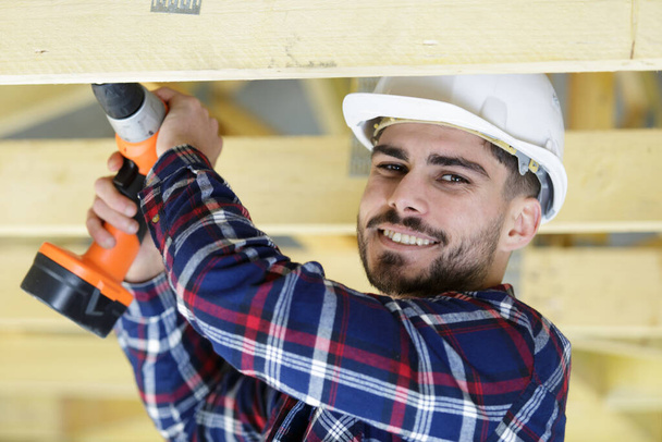 happy man drilling hole in wood - Photo, image