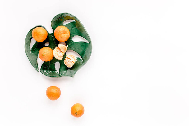 Ceramic plate-leaf Monstera with tangerines isolated on white background. Flat lay, top view.  - Fotografie, Obrázek
