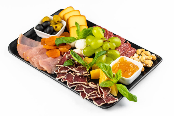 płyta mięsna z jamonem i plasterkami mięsa ozdobionymi winogronami i sosami na tle stołu - Zdjęcie, obraz