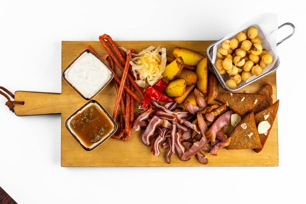 set van zoute snacks met sauzen op houten bord op witte tafel - Foto, afbeelding