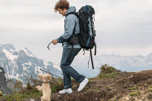 explorador alegre com uma vara entretendo seu cão enquanto caminhava na colina - Foto, Imagem