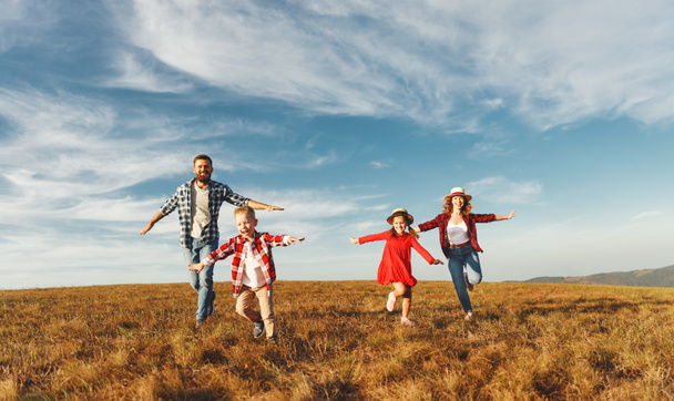 Familia feliz: madre, padre, hijos hijo e hija corriendo en la naturaleza en el sol - Foto, Imagen