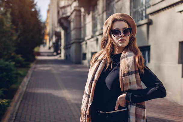 Kadın güzellik modası. Bej bereli, güneş gözlüklü ve eşarp tutan şık bir kadın. Sonbahar aksesuarları. Şehir caddesinde açık havada portre - Fotoğraf, Görsel