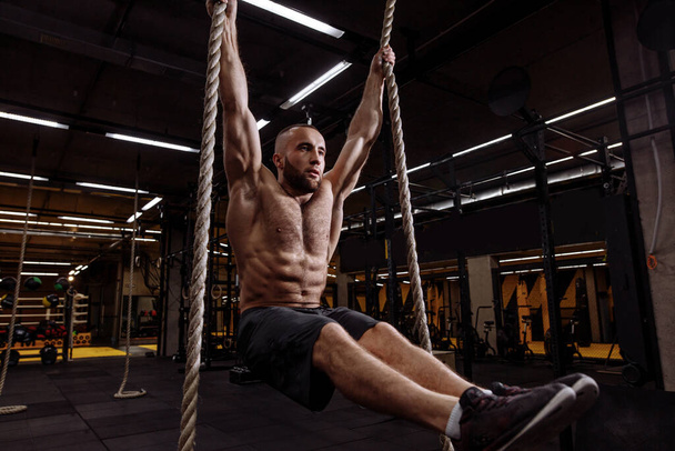 handsome athlete working out on two ropes at gym - Fotó, kép