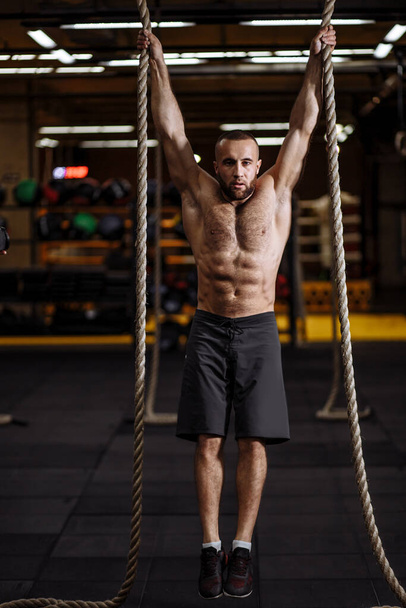 full length portrait. brutal fitness man is going to jump with ropes - 写真・画像