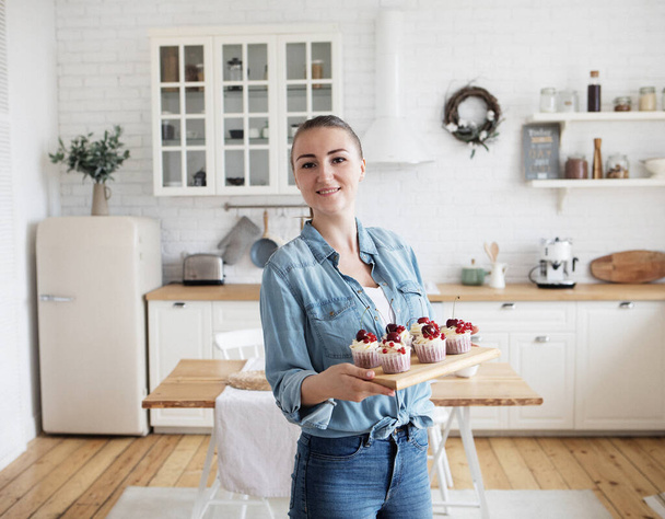 Young baker woman holding cupcakes. Happy, smiling and cheerful. - Foto, imagen