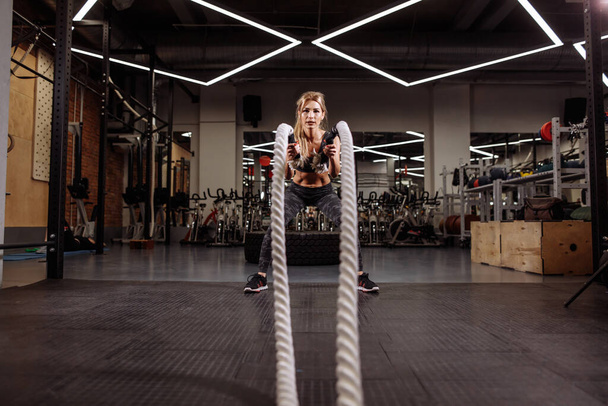 Strong muscular girl using battle ropes for exercise - Foto, Imagem