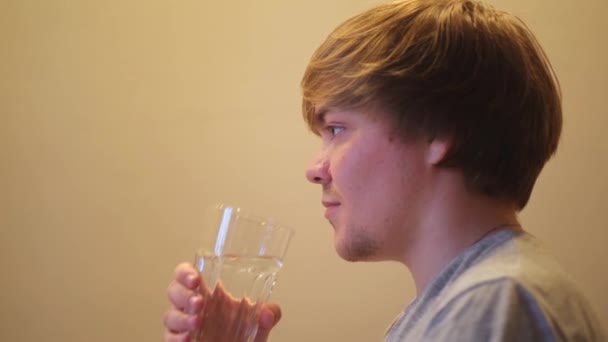 Jonge uitgedroogde man die gefilterd mineraalhelder water drinkt. Concept. Zijaanzicht van dorstige man met transparant glas en drinkwater, hydratatie en gezondheid concept. - Video