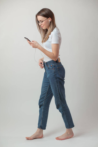 cheerful girl in casual clothes looking atthe smartphone while going somewhere - Fotoğraf, Görsel