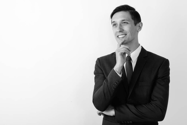 Студийный снимок молодого привлекательного бизнесмена в костюме на белом фоне в черно-белом - Фото, изображение