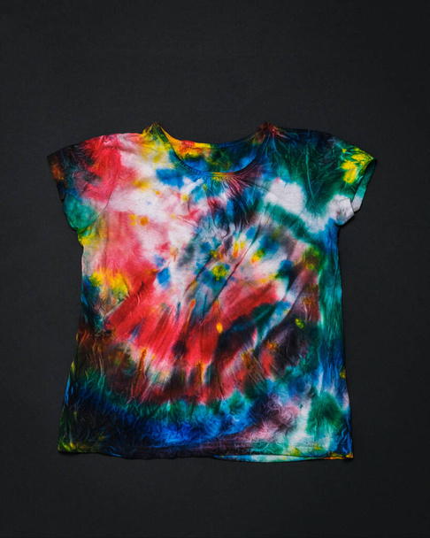 Colorful tie dye t-shirt on a black background. Flat lay. - Photo, Image