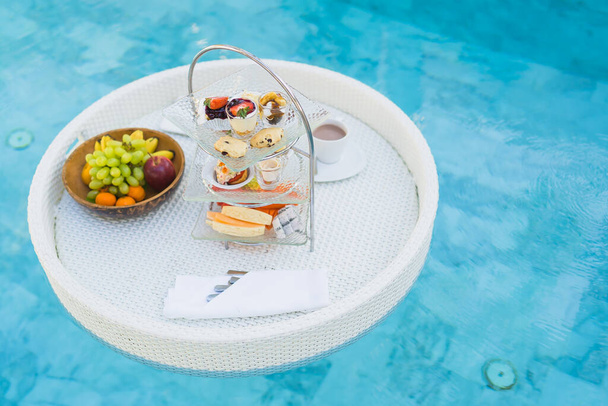 Breakfast and afternoon tea set floating around swimming pool in hotel resort - Foto, imagen