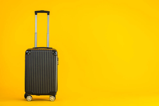 Uso de equipaje de color negro o bolsa de equipaje para viajes de transporte y ocio sobre fondo amarillo aislado - Foto, Imagen