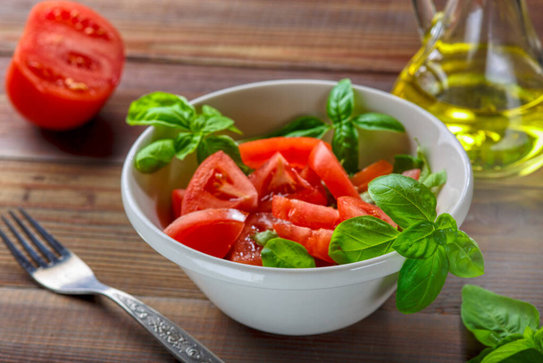 Salada de tomate com manjericão, azeite e vinagre balsâmico em tigela sobre fundo de madeira - Foto, Imagem