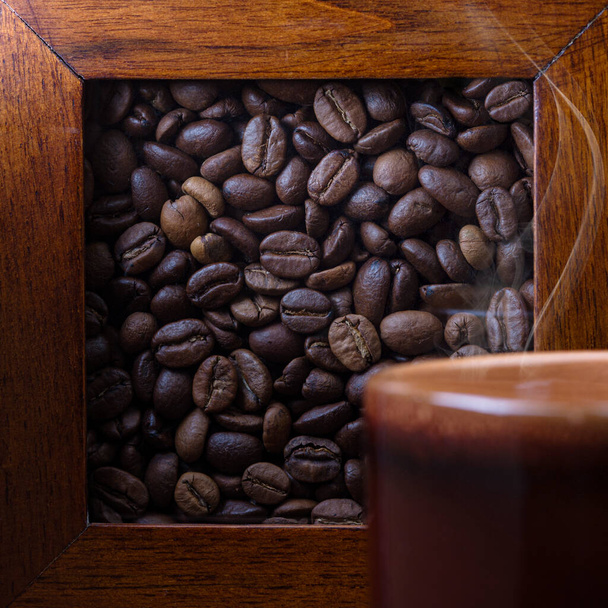 Fresh aromatic coffee in a coffee cup and coffee beans on the table. Dark background. - Photo, Image