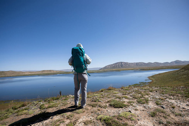 Sırt çantalı kişi yüksek irtifa gölü manzarasının tadını çıkarıyor - Fotoğraf, Görsel