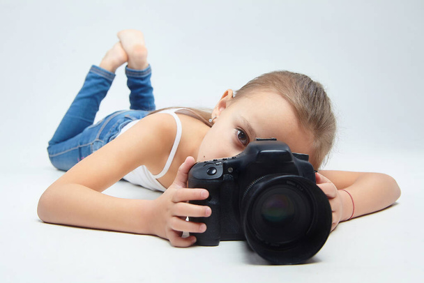 a little girl lies in the Studio with a camera. - Φωτογραφία, εικόνα