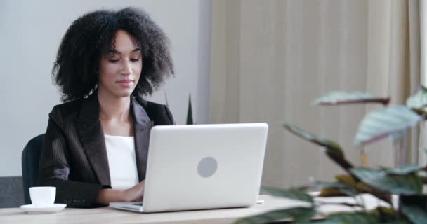 Зайнята жінка офісний працівник сидить за столом в компанії, працює серфінг Інтернету, використовує ноутбук для обробки інформації про дані, аналітики, роботи над проектом, отримує звіти з паперових документів для затвердження - Кадри, відео