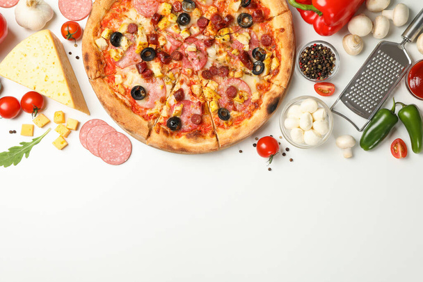 Lekkere pizza en ingrediënten op witte achtergrond, ruimte voor tekst - Foto, afbeelding