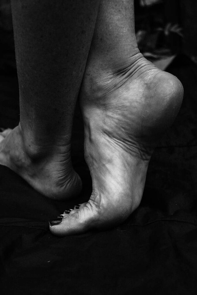 Female legs, hands. beautiful feet and palms on a black background, close-up. Black and white photography, natural light. - Foto, immagini