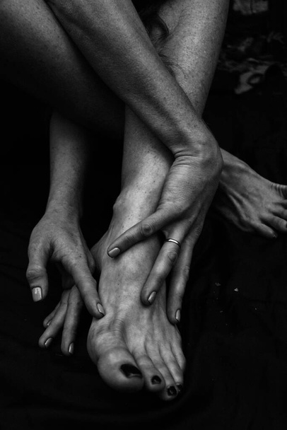 Female legs, hands. beautiful feet and palms on a black background, close-up. Black and white photography, natural light. - Valokuva, kuva