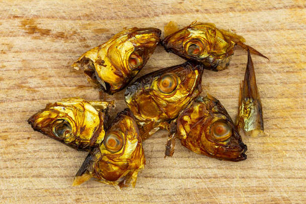Smoked sprat heads on wooden cutting board - Photo, Image