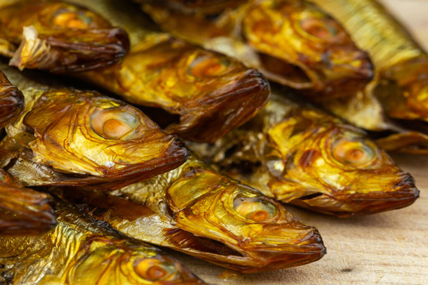 Golden, smoked sprats arranged on wooden cutting board - Photo, Image
