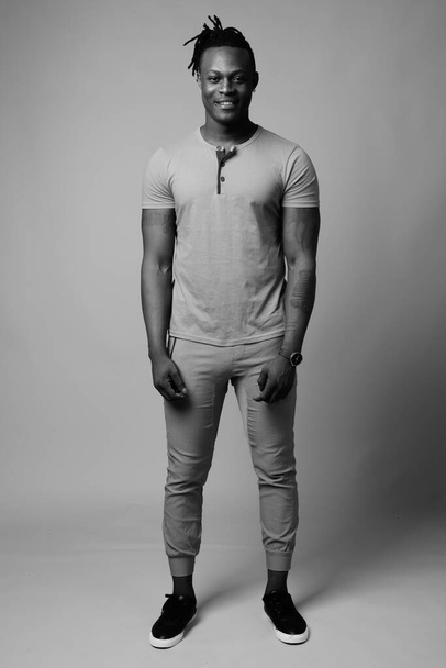 Estudio de un joven africano guapo de Kenia sobre fondo gris en blanco y negro - Foto, Imagen