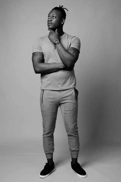 Studio shot of young handsome African man from Kenya against gray background in black and white - Photo, Image