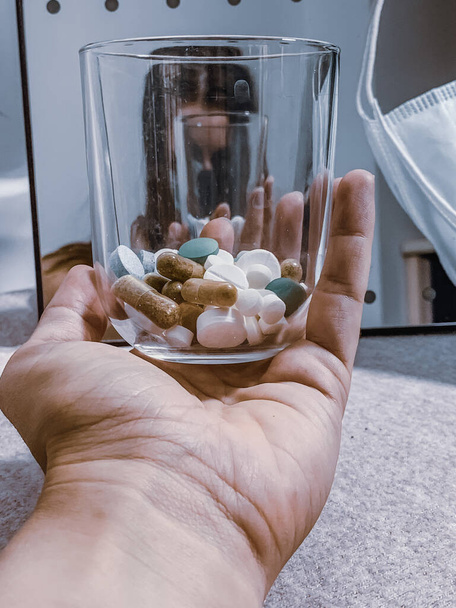 A vertical closeup shot of colorful pills in the glass - Zdjęcie, obraz
