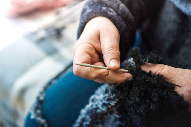 A closeup shot of female hands knitting with a fluffy fabric - Photo, image