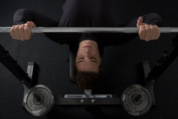 Une vue de dessus d'un jeune homme en forme faisant une presse de banc d'haltère à la salle de gym - Photo, image