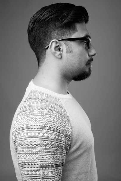 Studio shot of young bearded Iranian man wearing casual clothes against gray background in black and white - Fotó, kép