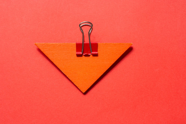 A closeup top view shot of a triangle held by a binder clip - Fotó, kép