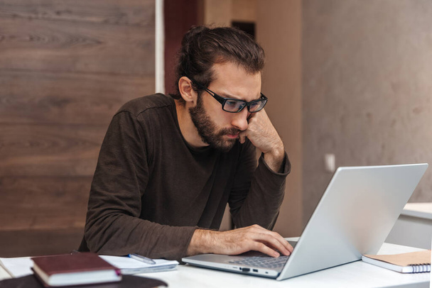Concentrated man in glasses working on laptop at home - Photo, Image