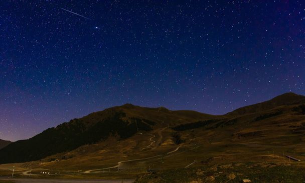 A panoramic shot of a mountain landscape on a stary night background - Foto, afbeelding