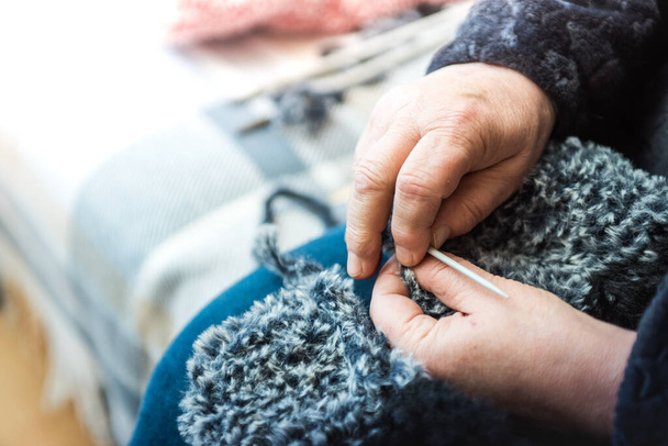 A closeup shot of female hands knitting with a fluffy fabric - Fotó, kép