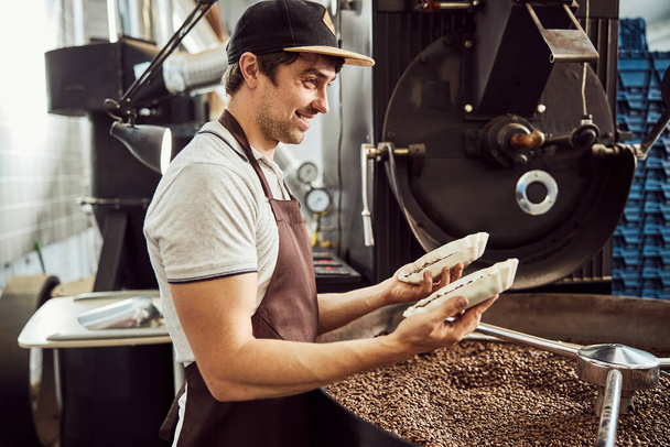 Travailleur masculin joyeux tenant deux bols avec des grains de café - Photo, image