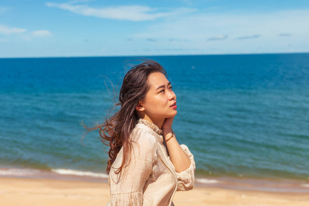 A young attractive Asian female model posing at the beach with the sea in the background - Foto, afbeelding