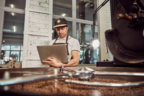 Handsome young man professional roaster using notebook at work - Foto, afbeelding