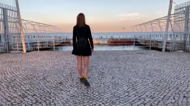 4k hidastettua kuvamateriaalia nuoresta kauniista naisesta kasvonaamiossa Covid-19:n puhkeamista vastaan Lissabonin kaupungissa (Portugali). Näkymä leikkisä tyttö kävely ulkona lipputangot takana - Materiaali, video