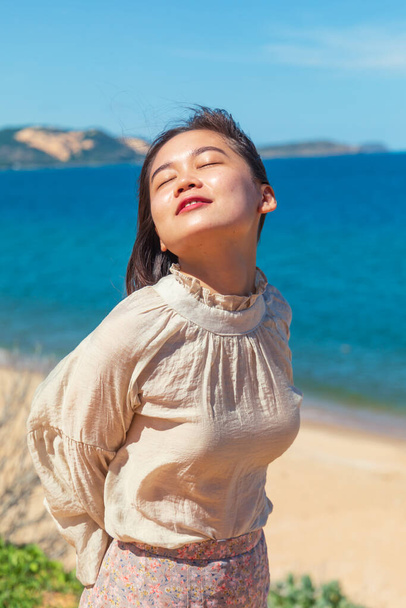 A vertical shot of a young attractive Asian female model enjoying the sunlight at the beach - Foto, Imagen